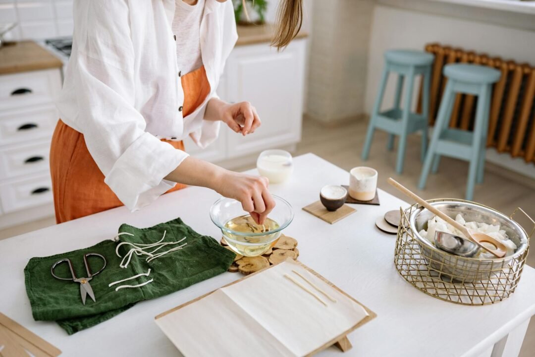 Artisan creates handmade candles in a cozy kitchen with tools and materials.
